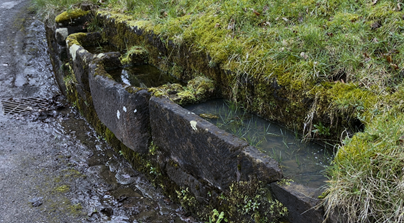 A water flowing through a stone wall
Description automatically generated